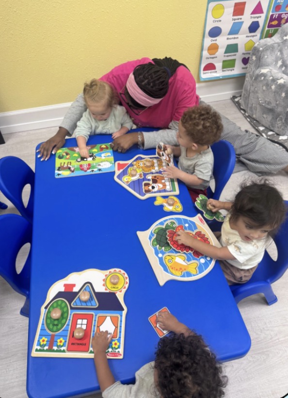 A Dreamland teacher helping toddlers explore puzzles together